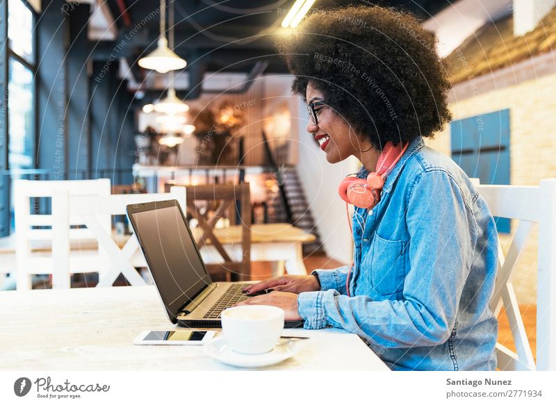 Beautiful afro american woman using mobile and laptop in the coffee shop. -  a Royalty Free Stock Photo from Photocase