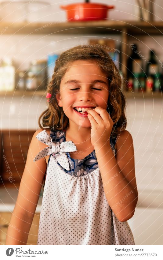 Little girl eating chocolate while preparing baking cookies. Girl Child Nutrition To feed savoring Eating enjoying Portrait photograph Appetite Smiling Laughter