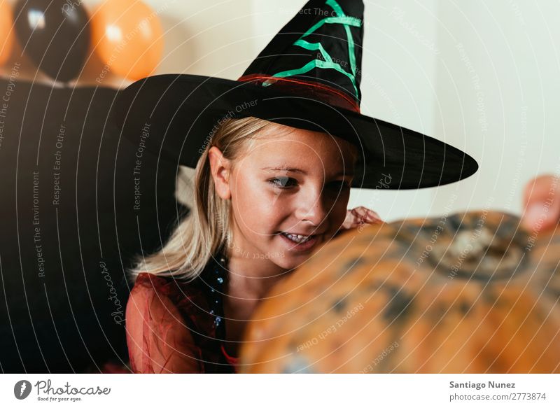 Beautiful girl disguised of witch decorating a pumpkin at home. Hallowe'en Child Girl Painting (action, artwork) Witch Disguised Joy Family & Relations Sister