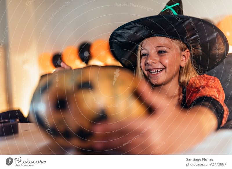 Beautiful girl disguised of witch decorating a pumpkin at home. Hallowe'en Child Girl Painting (action, artwork) Witch Disguised Joy Family & Relations Sister