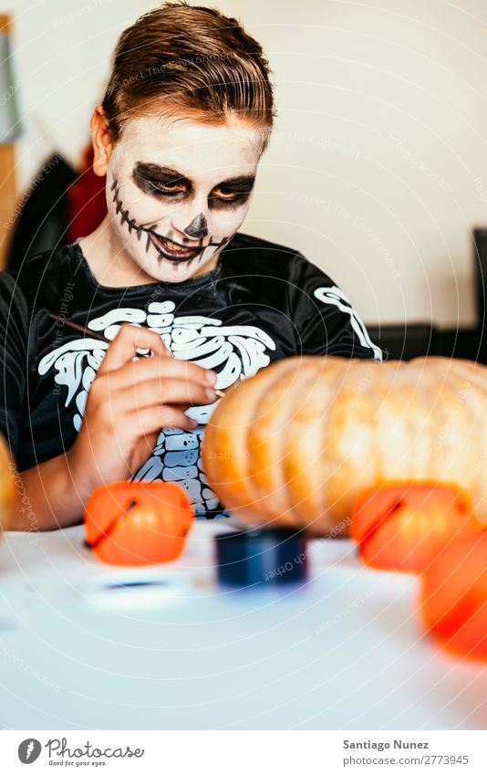 Happy boy disguised decorating a pumpkin at home. Halloween Concept. Hallowe'en Child Boy (child) Painting (action, artwork) Skeleton Joy Disguised