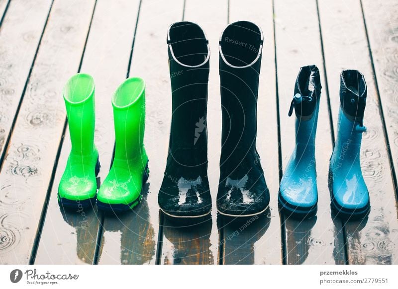 Row of wellies standing on a wooden porch while raining Joy Summer Child Human being Woman Adults Man Weather Rain Coat Footwear Boots Rubber boots Small Wet