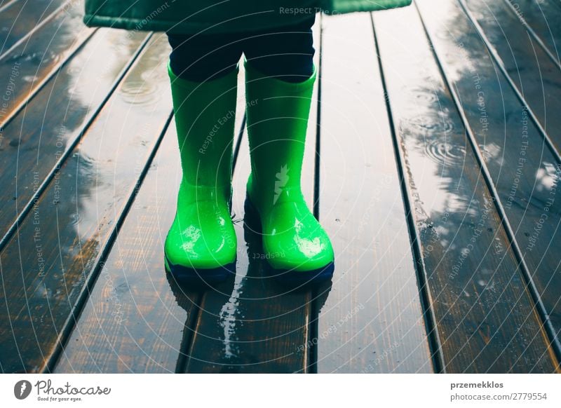 Kid standing on a porch wearing green wellies and raincoat Joy Summer Child Human being Boy (child) Weather Rain Coat Footwear Boots Rubber boots Small Wet Cute