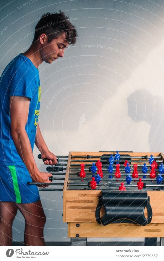 Young teenager boy playing table football with another player. Lifestyle Joy Relaxation Leisure and hobbies Playing Summer Table Sports Soccer Boy (child) Man