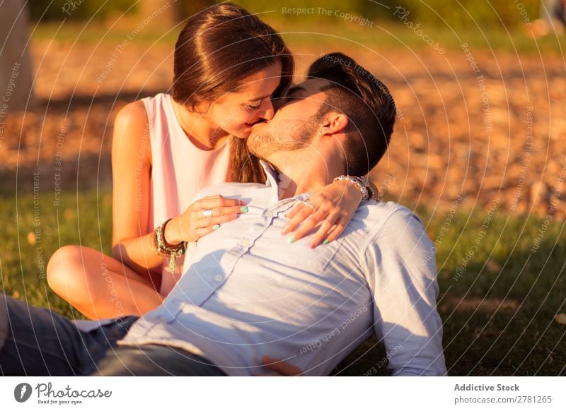 Bearded boyfriend lying on grass while kissing his girlfriend Couple Kissing Portrait photograph Sunlight Evening Park tender Love Sit Embrace Bright Grass Lawn