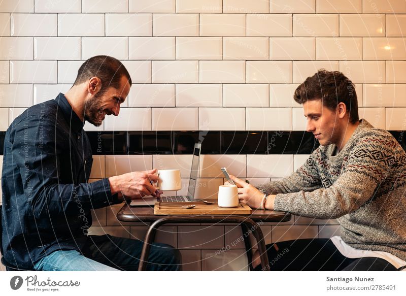 Friends using mobile and laptop. Man Coffee Friendship Youth (Young adults) Teamwork Group Human being Lifestyle PDA Cellphone Mobile Communication Text