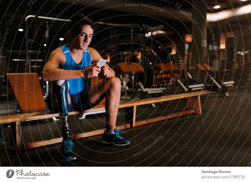 Disabled young man using his mobile in the gym. Man Youth (Young adults) Athlete Sports prothestic Portrait photograph Handicapped disabled paralympic Mobile