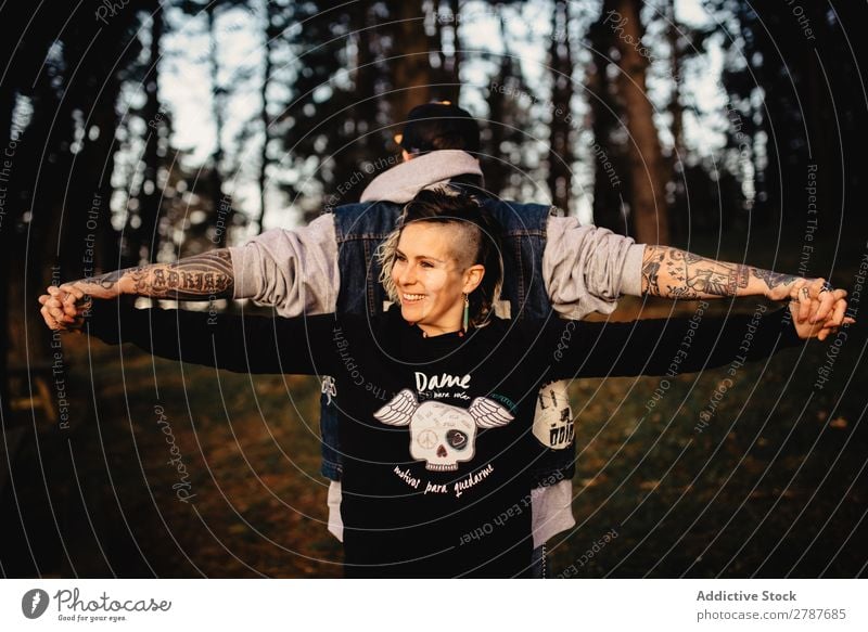 Young guy and happy lady standing back to back in forest Couple Tattoo Forest snapback Park Happy holding hands Lady Guy Youth (Young adults) Hipster Smiling