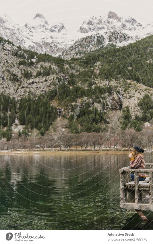 Woman on seat near wonderful lake between hills in snow and cloudy sky Lake Hill Seat Snow Pyrenees Sky Wonderful Water Surface Mountain Clouds Lady Height Tree