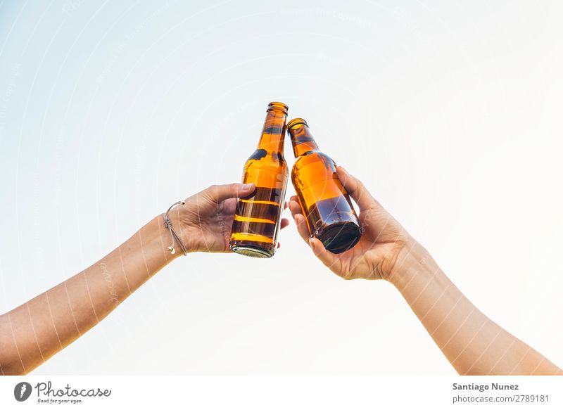 Female friends cheers clinking bottles of beer in hands. Beer Couple Toast Cheerful Glass Bottle Hand Woman Happy Background picture Feasts & Celebrations