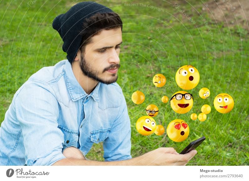 Young man using smartphone sending emojis. Lifestyle Happy Face Telephone PDA Screen Technology Internet Human being Man Adults Hand Funny Modern Smart Emotions