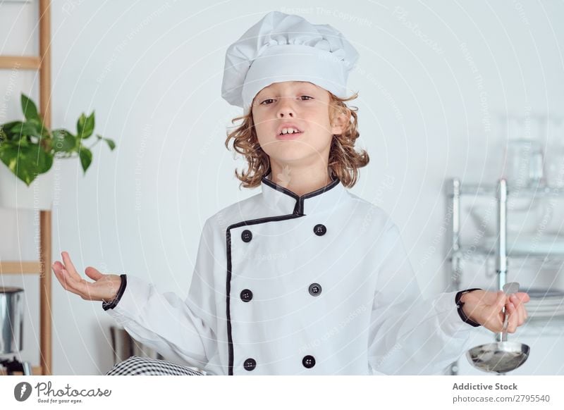 Boy in cook hat holding ladle and showing thumb up in kitchen Cook Boy (child) Kitchen Ladle chef Child Hat Cool (slang) Gesture Cooking Metal Modern Home