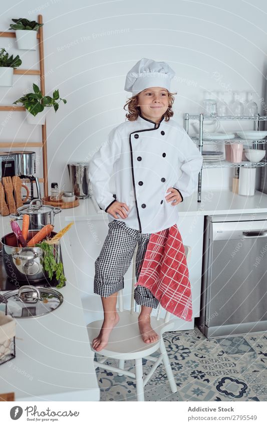 Boy in cook hat in kitchen Cook Boy (child) Kitchen Carrot chef Child Vegetable Hat Fresh Indicate Hand Hip Cooking Modern Funny Home Light preparing Happiness