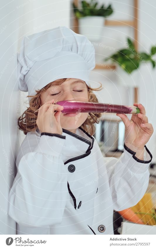 Boy in cook hat holding vegetable in kitchen Cook Boy (child) Kitchen Vegetable chef Child Hat smelling Closed eyes Fresh Cooking Modern Funny Home Light