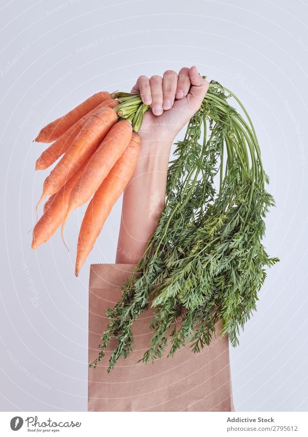 Person hand reached out from packet and holding carrots Human being Hand Carrot Package Vegetable Food Bag Craft (trade) Paper Conceptual design Fresh Markets
