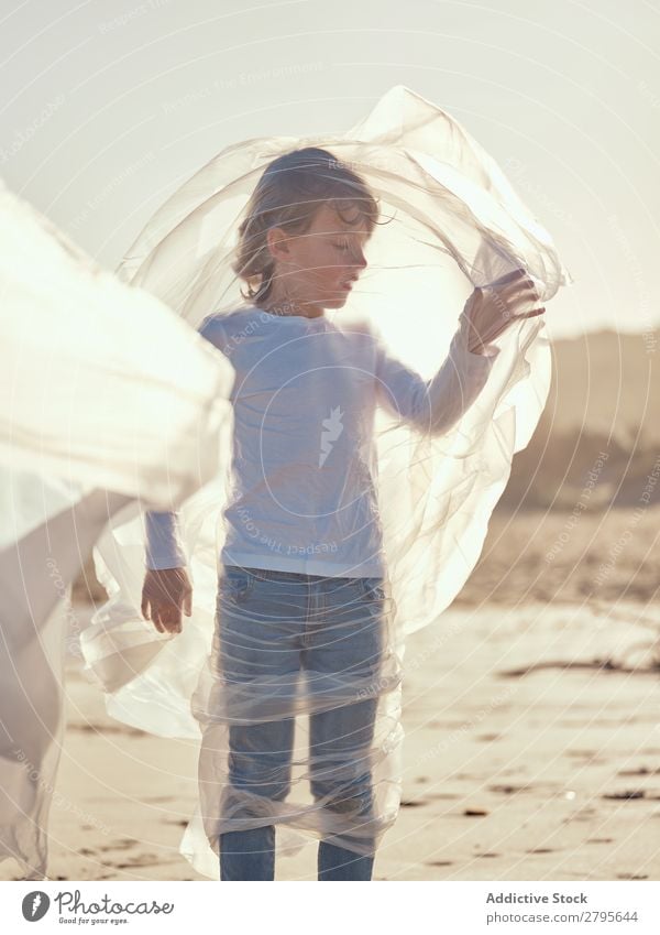 Child entangled in plastic on river coast Boy (child) Plastic textile waving River Coast Side Wind Sand Water Mountain Landscape Beach Help White Sun Joy