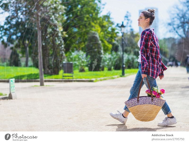 Side view of a young hipster woman holding a wicker basket while walking in a park in sunny day Profile Young woman Hipster Hold Wicker basket Basket Walking