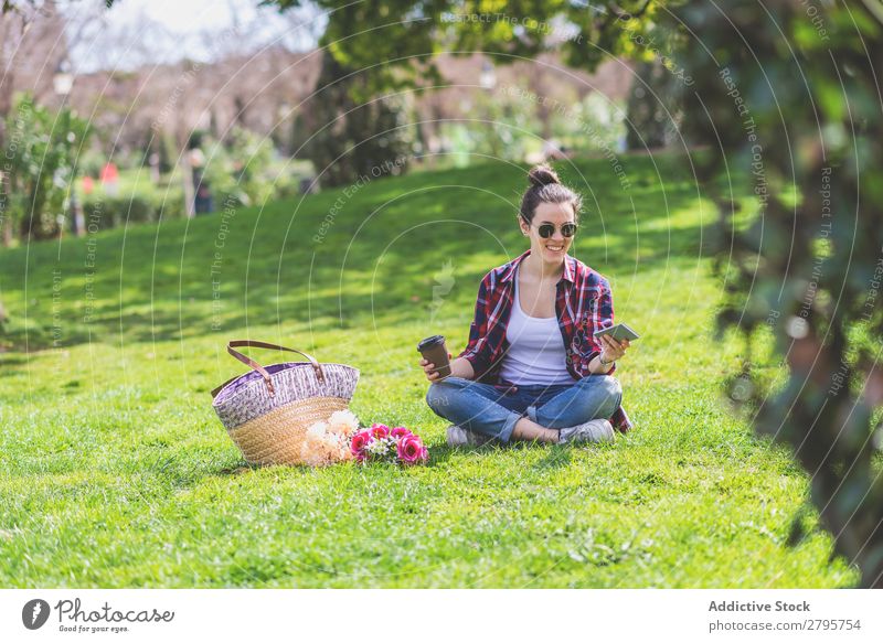 Front view of a young hipster woman sitting on grass in a park Young woman Hipster Hip & trendy Sit Park Grass using Ground Cellphone Smiling Relaxation Sunbeam