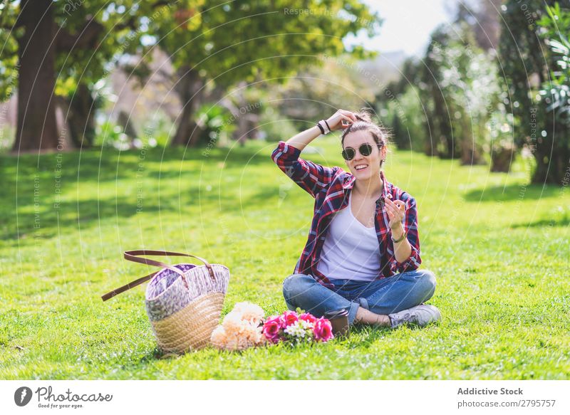 Front view of a young hipster woman sitting on grass in a park while holding a flower and smiling in a sunny day Woman Young woman Hipster Hip & trendy Sit Hold