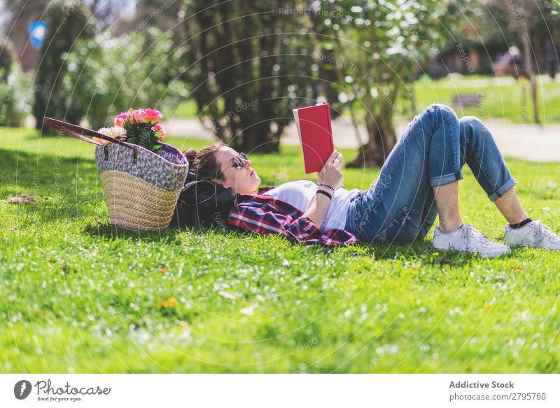Side view of a hipster happy woman lying on grass in sunny day at park while reading a red book Profile Young woman Hipster Hip & trendy Lie (Untruth) Reading