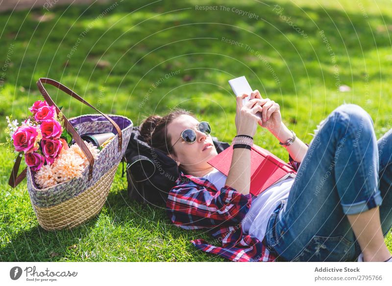 Side view of a hipster happy woman lying on grass in sunny day at park while reading a red book Profile Young woman Hipster Hip & trendy Lie (Untruth) using
