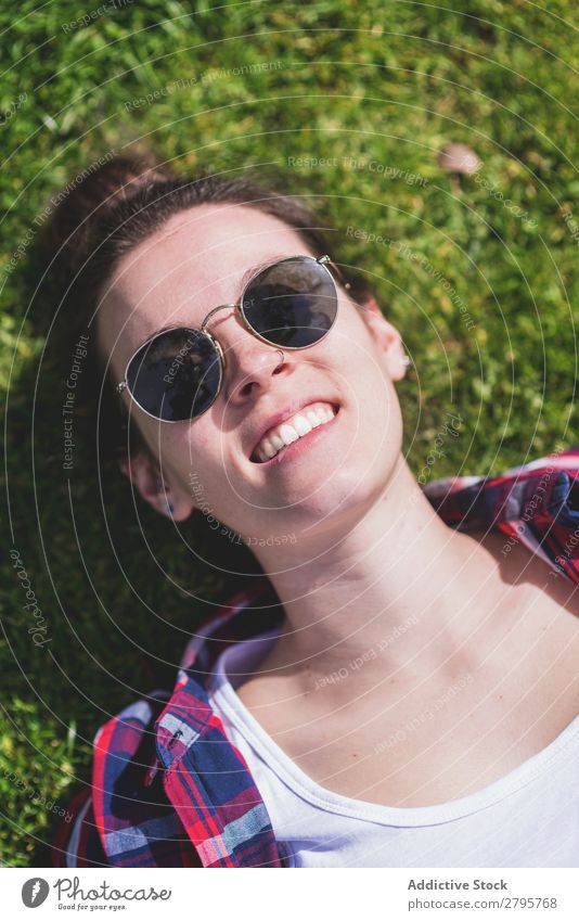 Above view of a young smiling hipster woman lying on grass in a sunny day at a park while taking a selfie with a mobile phone Young woman Hipster Hip & trendy