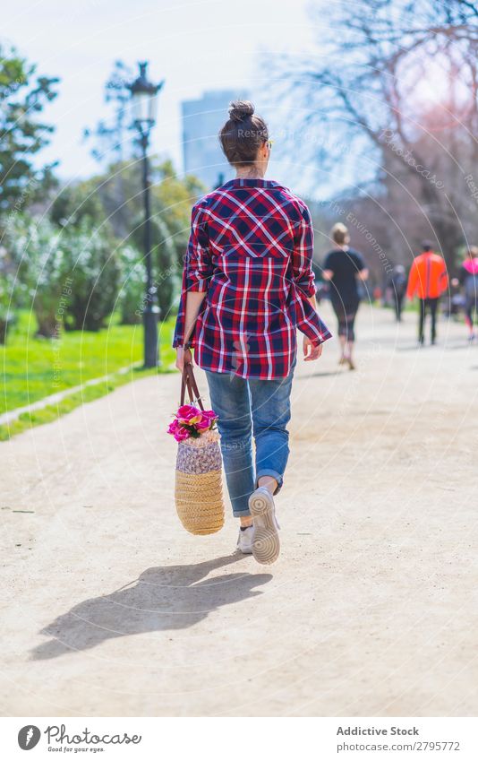 Rear view of a young hipster woman walking in a park in sunny day while holding a wicked basket Woman Young woman Hipster Walking Hip & trendy Park Relaxation