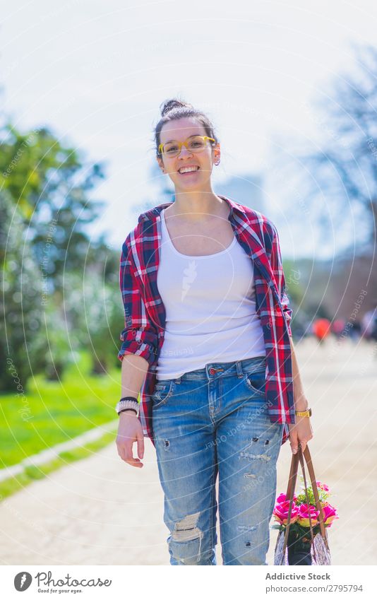 Front view of a young smiling hipster woman walking in a park in sunny day while holding a wicked basket Young woman Hipster Walking Smiling Hip & trendy Park