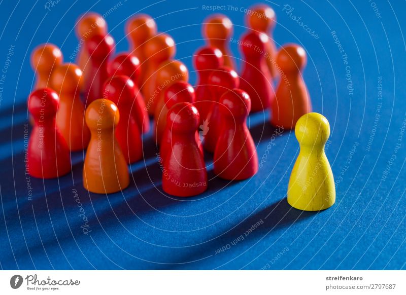 A single yellow playing piece stands opposite a group of red playing pieces on a blue background Study Professional training Economy Business Career Success