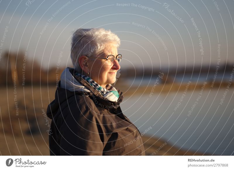 Senior woman with view at the lake Gray-haired Old Peaceful Exterior shot Landscape Sunlight Idyll Beautiful weather Sky silent Calm Human being evening light