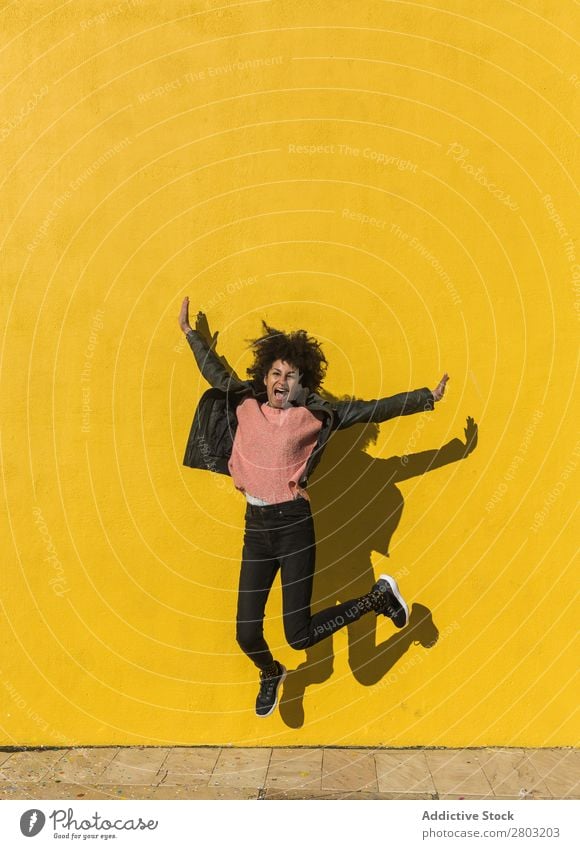 Black woman with afro hair jumping for joy in the street. African Afro American Background picture Beautiful Easygoing Cheerful Colour Energy enjoyment Fashion