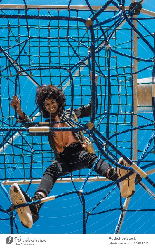 Woman with afro hair climbing by children's attractions. Action African Afro Black Cheerful Infancy Climbing Cute Equipment Family & Relations Joy Girl Happy