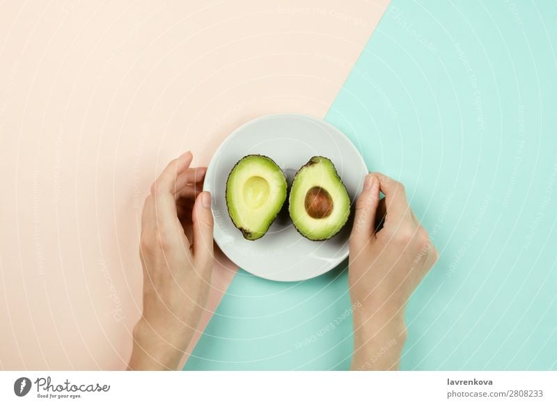 Cut avocado on white plate and woman's hands Vegetarian diet Vegan diet Fruit Eating flat lay Plate Ingredients Diet Healthy Healthy Eating Pastel tone Woman