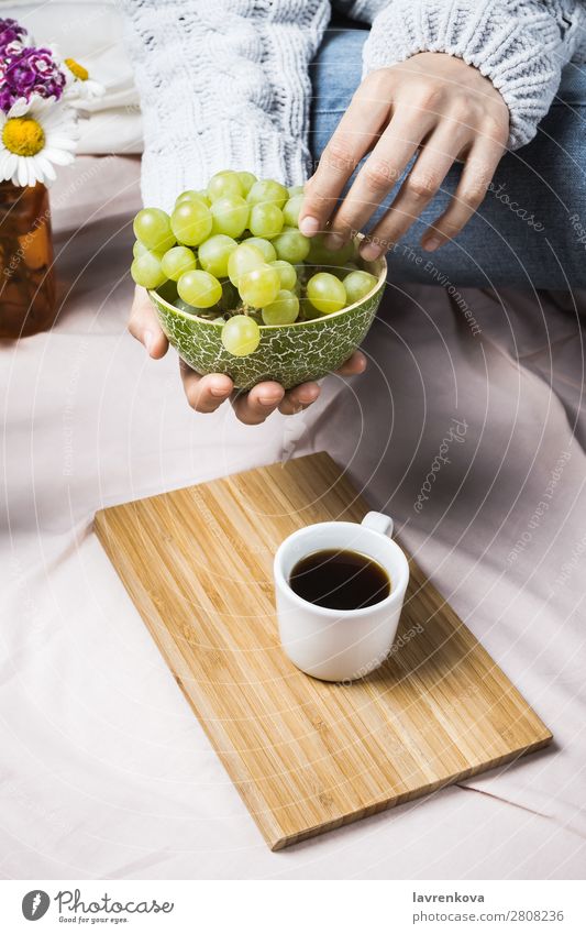 Woman's hands in sweater holding wooden bowl with grapes Autumn Harvest Cozy Natural Summer Fresh Close-up Fruit Organic Mature Eating Bed Bedclothes Blanket