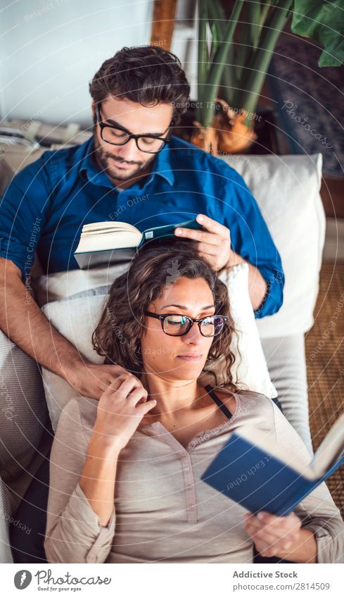 Young couple reading book on couch at home Book Home Literature Sofa Leisure and hobbies closeness Attractive Denim Vantage point Sit Day Life Adults fondness