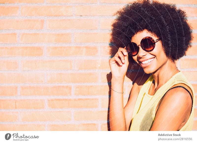 Young beautiful Afro-American woman posing and smiling while standing against brick wall African Charming Brick Model Hand Attractive Curly Sincere Happiness