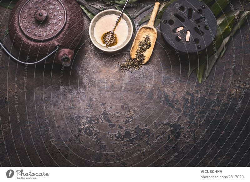 Traditional Asian green tea background with black iron teapot, candle and honey on dark rustic background with copy space, top view traditional asian sencha