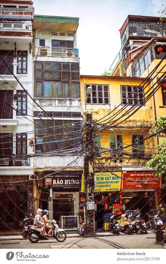 HANOI, VIETNAM - JUNE 17, 2015: Motorcycles running on a typical street in Hanoi with many electric poles and wires across, on June 17, 2015, in Hanoi, Vietmam