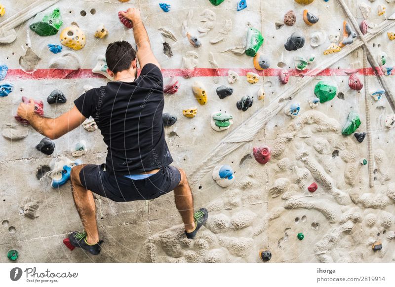 Man practicing rock climbing on artificial wall indoors Lifestyle Joy Leisure and hobbies Sports Climbing Mountaineering Human being Young man