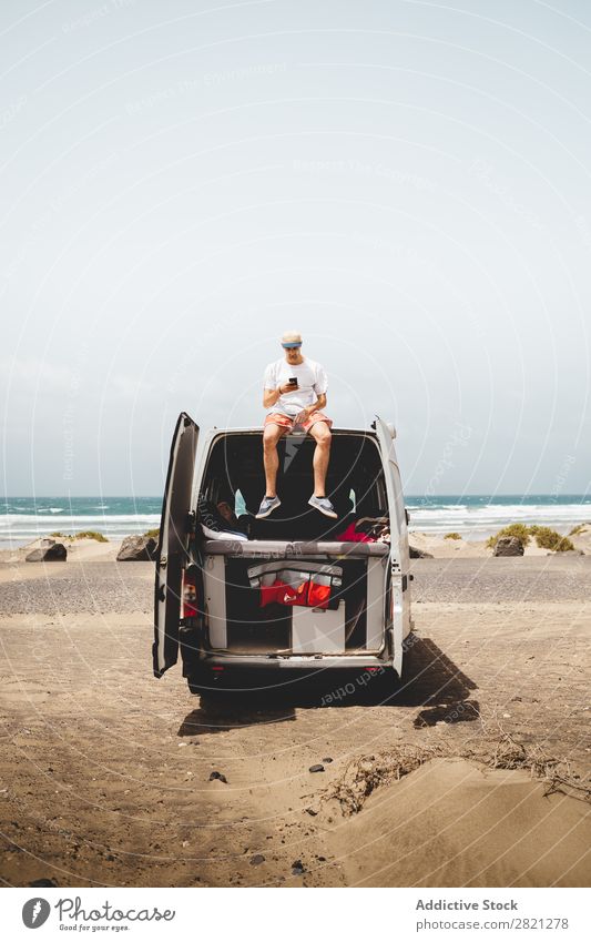 Man using phone on van Van Roof Sit seaside PDA browsing communicating Surfing Gadget device Relaxation Street Human being Vantage point Trip Vacation & Travel