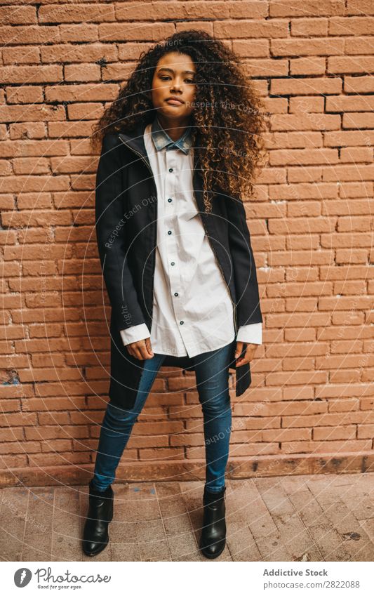 Stylish woman at brick wall Woman pretty Beautiful Ethnic Black Curly Youth (Young adults) Stand Looking into the camera Wall (building) Brick Street Brunette