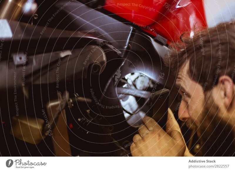 Man using light to look into bike Employees &amp; Colleagues Human being Light Looking inspecting Motorcycle Workshop Parked Engines Transport Vehicle Garage