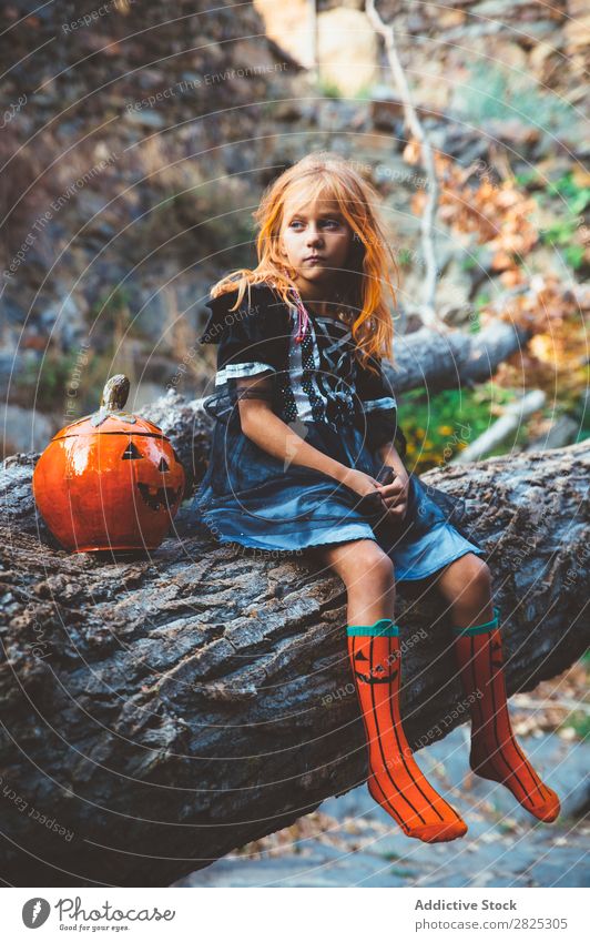 Cheerful kid in costume posing on tree Girl Costume Hallowe'en Posture Feasts & Celebrations Tradition Magic Expression Candy Clothing Tree trunk Festival