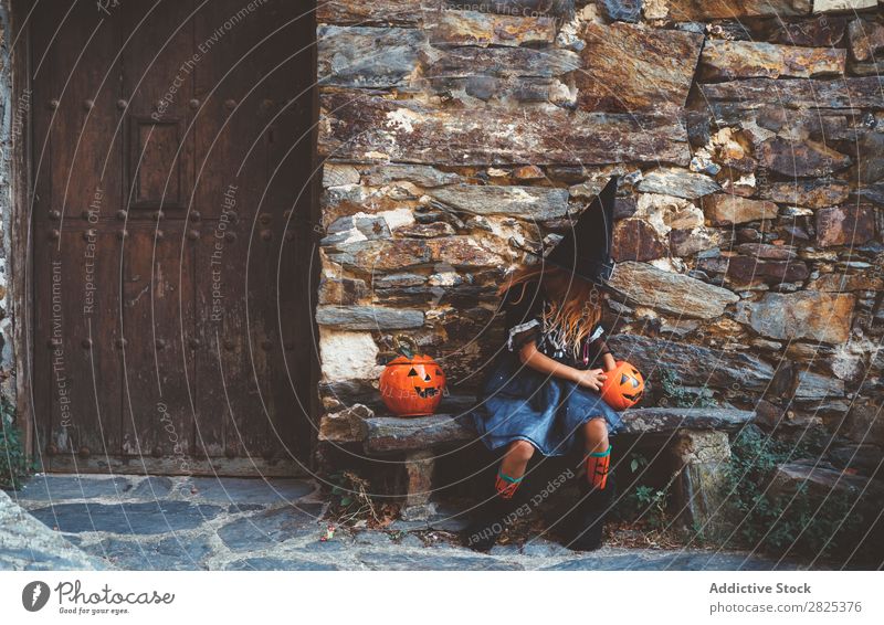 Little girl in witch costume sitting on bench Girl Hallowe'en Candy Bench Dog food Vacation & Travel Entertainment Festival Seasons Costume Tradition Sweet