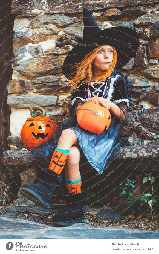 Little girl in witch costume sitting on bench Girl Hallowe'en Candy Eating Bench Dog food Vacation & Travel Entertainment Festival Seasons Costume Tradition