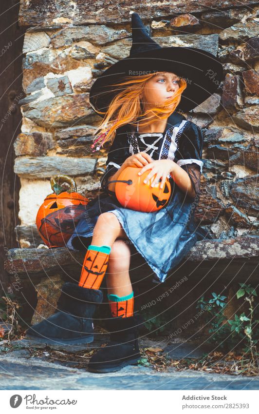 Little girl in witch costume sitting on bench Girl Hallowe'en Candy Eating Bench Dog food Vacation & Travel Entertainment Festival Seasons Costume Tradition