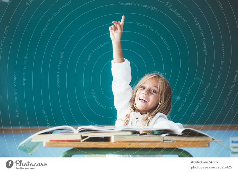 Happy schoolgirl with hand up Girl Classroom Blackboard Sit Desk Smiling Answer Cute Education School Grade (school level) Student Youth (Young adults) Study