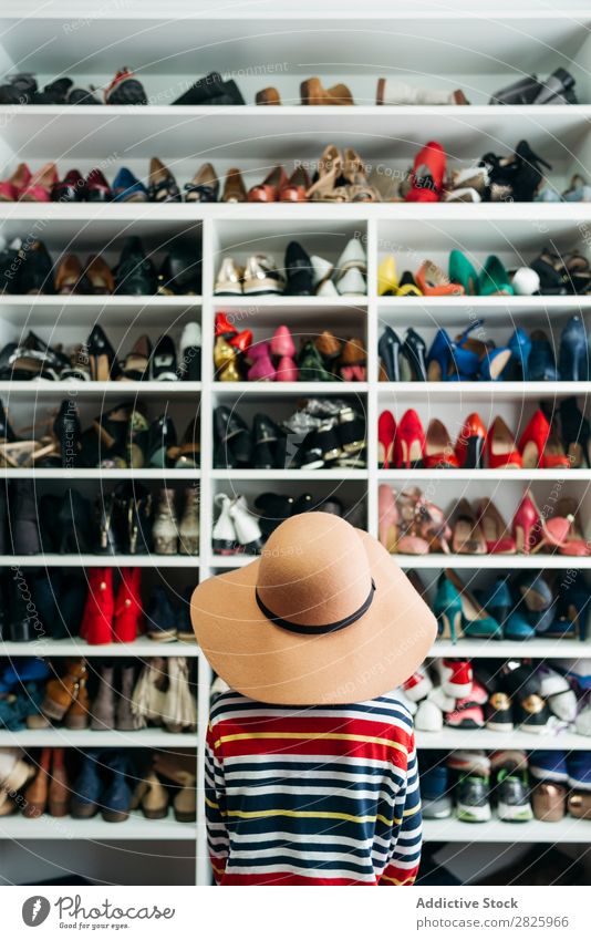 Person in front of shelves with different shoes Human being Rear view Anonymous Unrecognizable Hat Rack Cupboard Footwear shelf Fashion Storage Style Closet