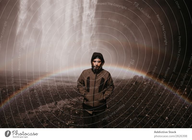 Young man in coat on waterfall Man Waterfall Rainbow Iceland Stream Fog Tourism Mountain Natural Vacation & Travel Landscape Environment Powerful Flow Energy