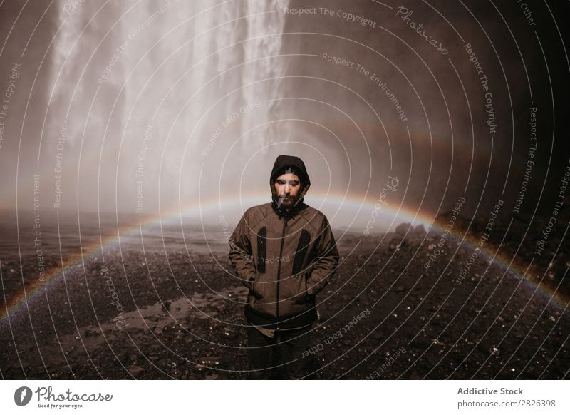 Young man in coat on waterfall Man Waterfall Rainbow Iceland Stream Fog Tourism Mountain Natural Vacation & Travel Landscape Environment Powerful Flow Energy